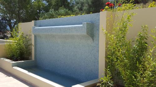 a stone wall with a water fountain in a garden at Ionian Vista Villas in Argostoli