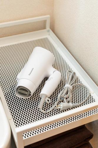a white holder with a hair dryer and scissors at Koubun Room Yokohama Hiyoshi Vacation Rental in Yokohama