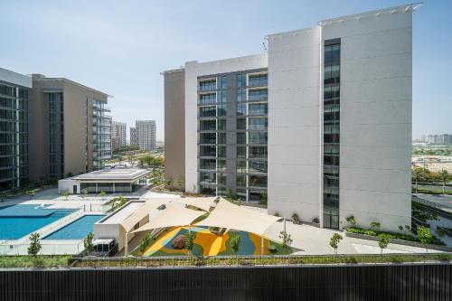 a pool with an umbrella in front of a building at Luxury unit in the Heart of Dubai Hills in Dubai