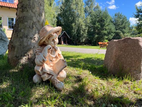 a statue of a little boy sitting next to a tree at Dworek Na Uboczu in Sulicice