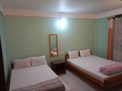 two beds in a room with a mirror at Cozy Inn in Cherrapunji