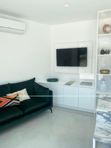 a living room with a black couch and a tv at White Olive Villas in Santarém