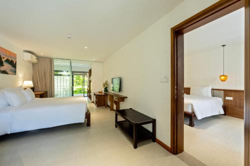 a hotel room with two beds and a mirror at Shoreline Stay in Hoi An