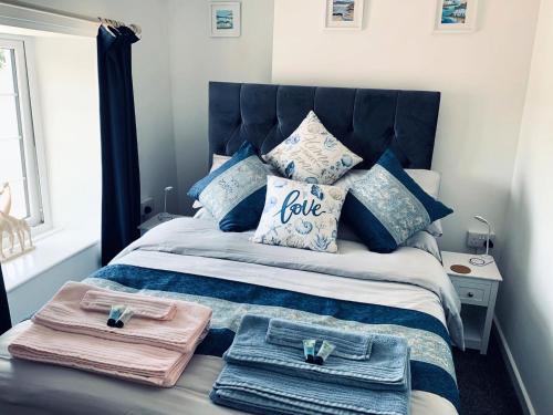 a bed with blue pillows and towels on it at Holm Cottage near Charlestown in St Austell