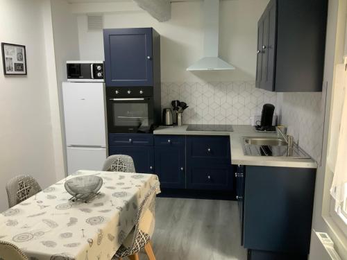 une cuisine avec une table et une cuisine avec des armoires bleues dans l'établissement les gites de KALY, à Bélesta