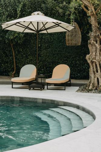 two chairs and an umbrella next to a swimming pool at The Bold Type Hotel, a Member of Design Hotels in Patra