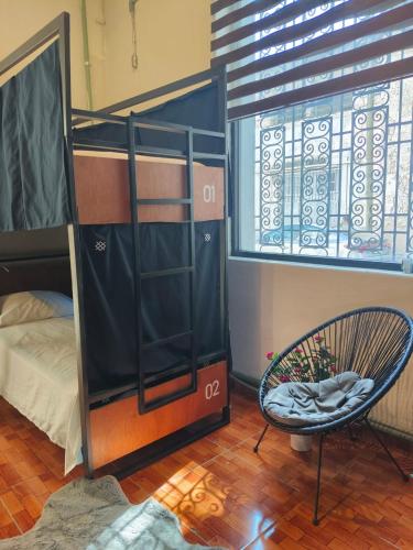 a dorm room with a bunk bed and a chair at Kambal Peregrino in Mérida