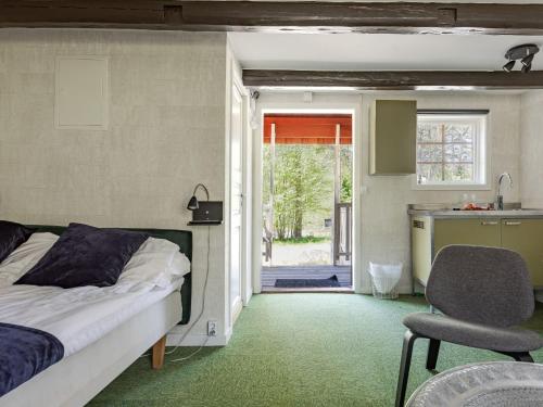 a bedroom with a bed and a chair and a kitchen at Holiday Home Himla by Interhome in Hudiksvall