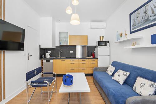 un salon avec un canapé bleu et une cuisine dans l'établissement Centre de Cannes 1 Bedroom, 131 Rue d'Antibes à 5 minutes du palais, à Cannes