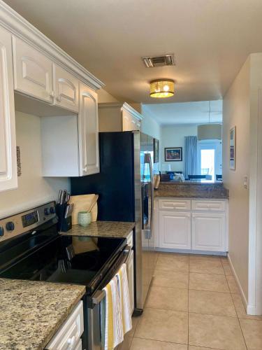 a kitchen with white cabinets and black counter tops at NEW Oceanfront Condo in George Town in George Town