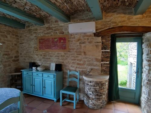a room with a table and a chair in a stone wall at La petite maison aux lézards in Le Garn