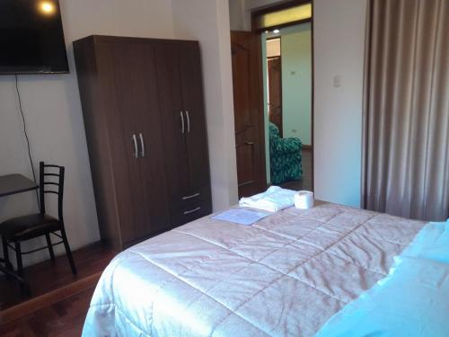 a bedroom with a bed with a dresser and a mirror at Hotel Valle Dorado in Huancayo