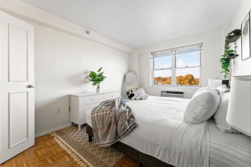 a white bedroom with a large bed and a window at Furnished Apartment in Brookline
