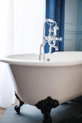 a white bath tub with a faucet in a bathroom at Gite de charme Le Quatre Feuilles in Montournais