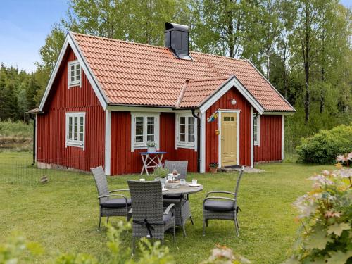 a red cottage with a table and chairs in the yard at Holiday Home Bygget by Interhome in Simlångsdalen