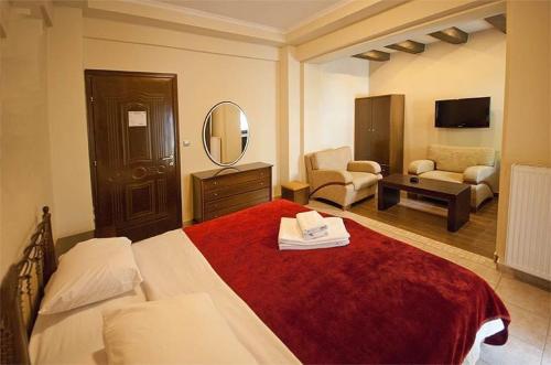 a bedroom with a large bed with a red blanket at Nostos Hotel in Kato Loutraki