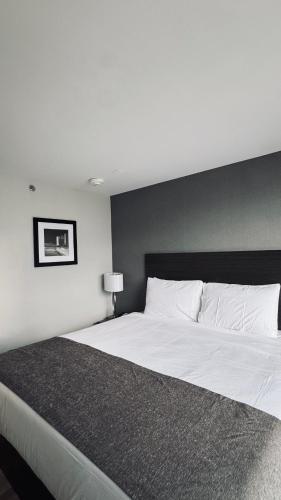 a bedroom with a large white bed with a black headboard at Capital Hotel Long Island City in Queens