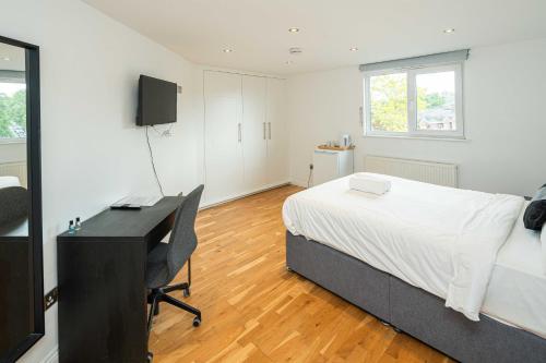 a bedroom with a bed and a desk with a computer at SE10 House in London