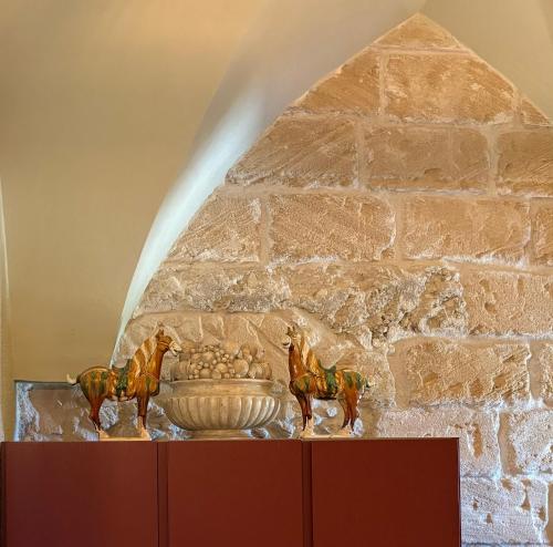 a statue of horses next to a vase in front of a stone wall at Dimora Spugnara in Lampedusa