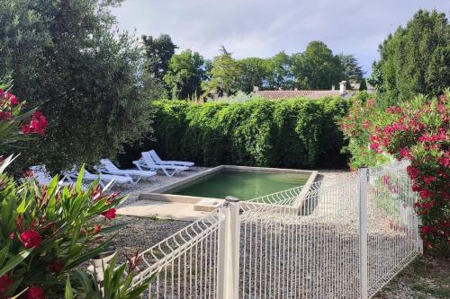 a fence with a pool in a garden with flowers at Domaine Guiton Le Colombier in Chamaret