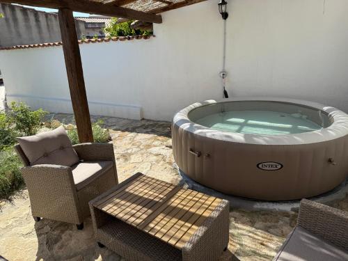 a hot tub on a patio with a chair and a table at Way to the sea - Home with garden & hot tub in Càbras