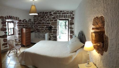 une chambre avec un lit dans un mur de pierre dans l'établissement Maison de caractère, à Chambonas