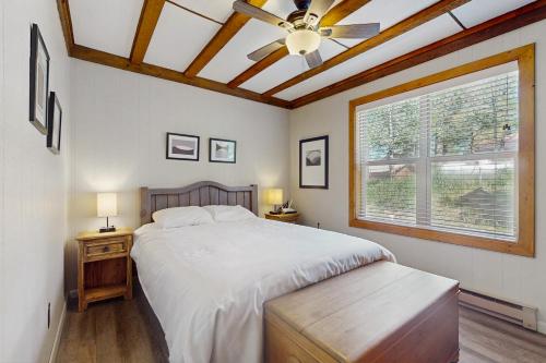 a bedroom with a bed with a ceiling fan and a window at Timbers Five in Angel Fire