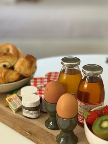 een tafel met eieren en brood en een schaal fruit bij Suite Élan by CollectionAura - Hypercentre Charleville-Mézières in Charleville-Mézières