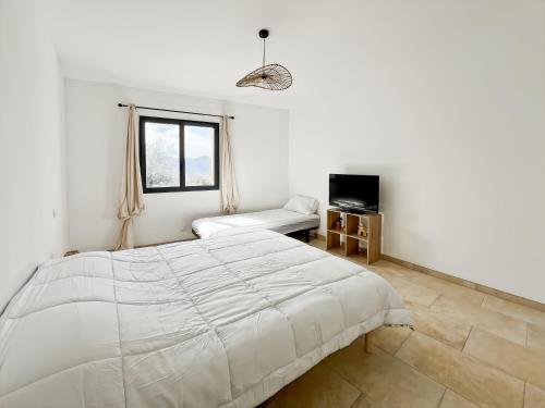 - une chambre blanche avec un grand lit et un canapé dans l'établissement Belle maison de village Corbara, à Corbara