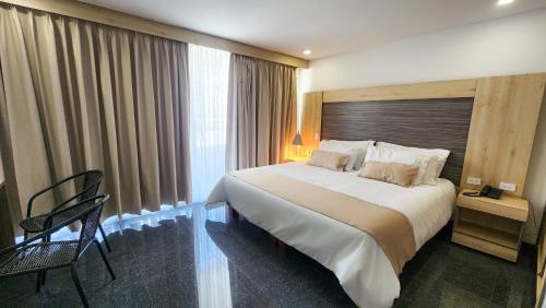 a hotel room with a large bed and a chair at Hotel BE Suites Cali in Cali
