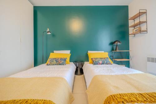 - 2 lits dans une chambre avec un mur bleu dans l'établissement Les roseaux bleus, à La Rochelle