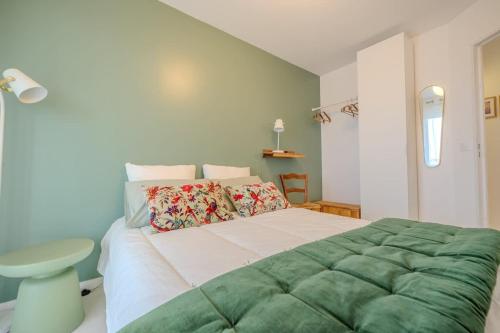 une chambre avec un grand lit avec une couverture verte dans l'établissement Les roseaux bleus, à La Rochelle