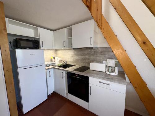 une cuisine avec des armoires blanches et un réfrigérateur blanc dans l'établissement Maison confortable près de la forêt pour 4 personnes avec parking privatif - FR-1-323-581, à Saint-Jean-de-Monts