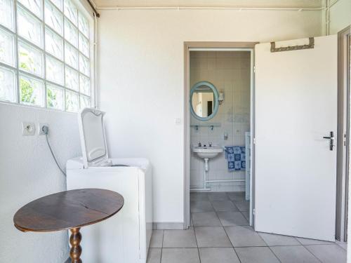 La salle de bains est pourvue d'un évier, d'un réfrigérateur et d'une table. dans l'établissement Maison à Mimizan Plage Sud avec jardin pour 4 personnes - Ménage inclus - FR-1-50-182, à Mimizan