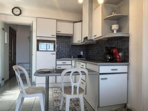 une cuisine avec des armoires blanches et une table et des chaises dans l'établissement Maison Méditerranéenne 2 Pers avec Garage - FR-1-225C-178, à Banyuls-sur-Mer