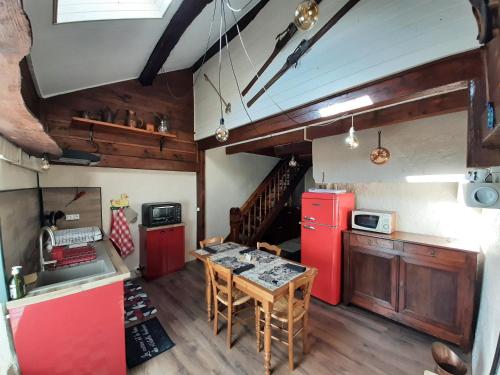 Il comprend une cuisine équipée d'un réfrigérateur rouge et d'une table. dans l'établissement Gîte paisible dans une ancienne ferme avec WIFI et parking à Saint-Bresson - FR-1-583-440, à Saint-Bresson