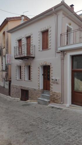 a white building with a balcony and a door at Agiasos House in Agiásos
