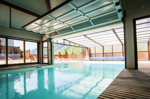 an indoor swimming pool with glass windows and a large pool at Les Balcons de La Neste - Appt 5-6 pers, Balcon et Vue Montagne in Arreau