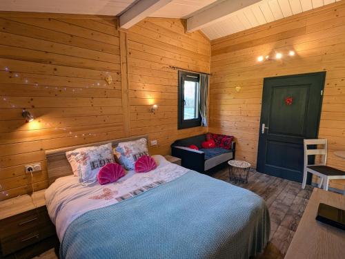 ein Schlafzimmer mit einem Bett in einem Holzzimmer in der Unterkunft Chalet détente avec Spa et animaux admis près de Plombières-les-Bains - FR-1-583-498 in La Vaivre