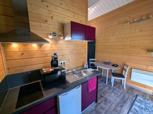 une cuisine avec un évier et une cuisinière dans l'établissement Chalet détente avec Spa et animaux admis près de Plombières-les-Bains - FR-1-583-498, à La Vaivre