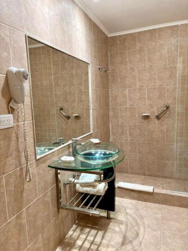 a bathroom with a glass sink and a mirror at Hotel Rio Sauce in Sierra de la Ventana