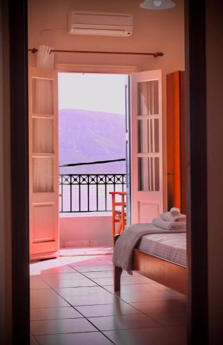 a bedroom with a bed and a view of a balcony at Kalymnos Skalia Mountain-Sea in Skaliá