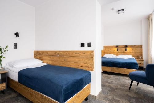 a bedroom with two beds and a chair at Hotel Rzemieślnik Zakopane in Zakopane