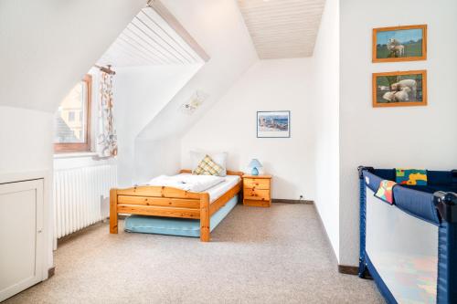 a small bedroom with a bed and a crib at Haus Sonnenblume in Oldenswort