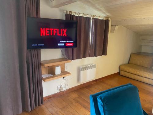 une télévision sur un mur dans une pièce avec un canapé dans l'établissement Appartement 71m2 près de Megève, 2 chambres, terrasse en toiture, parking couvert, tennis en été, à Demi-Quartier