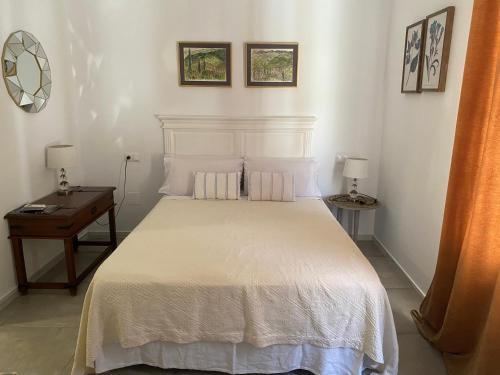 a bedroom with a white bed and a table at El nido del Chorro in Málaga
