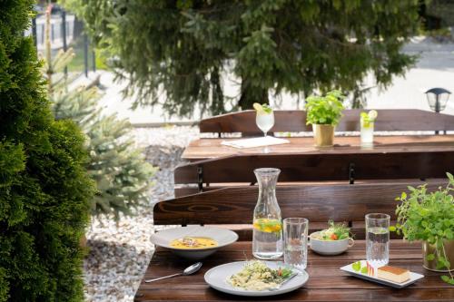 a wooden table with plates of food and glasses of water at Hotel Rzemieślnik Zakopane in Zakopane