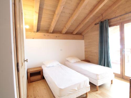 deux lits dans une chambre avec un plafond en bois dans l'établissement Appartement 3P cosy, cheminée, WIFI, garage, proche pistes et commerces - FR-1-572-240, aux Carroz d'Arâches