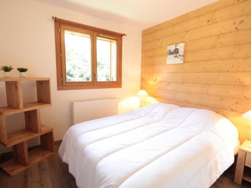 - une chambre avec un lit blanc et un mur en bois dans l'établissement Spacieux 4 pièces, 6 couchages, terrasse, près pistes et commerces, parking couvert, casier à skis - FR-1-572-244, aux Carroz d'Arâches