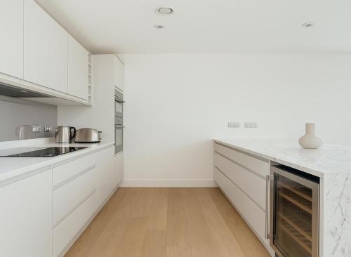 a white kitchen with white cabinets and a wooden floor at Premium 2 Bed Flat near Colindale Station in Colindale